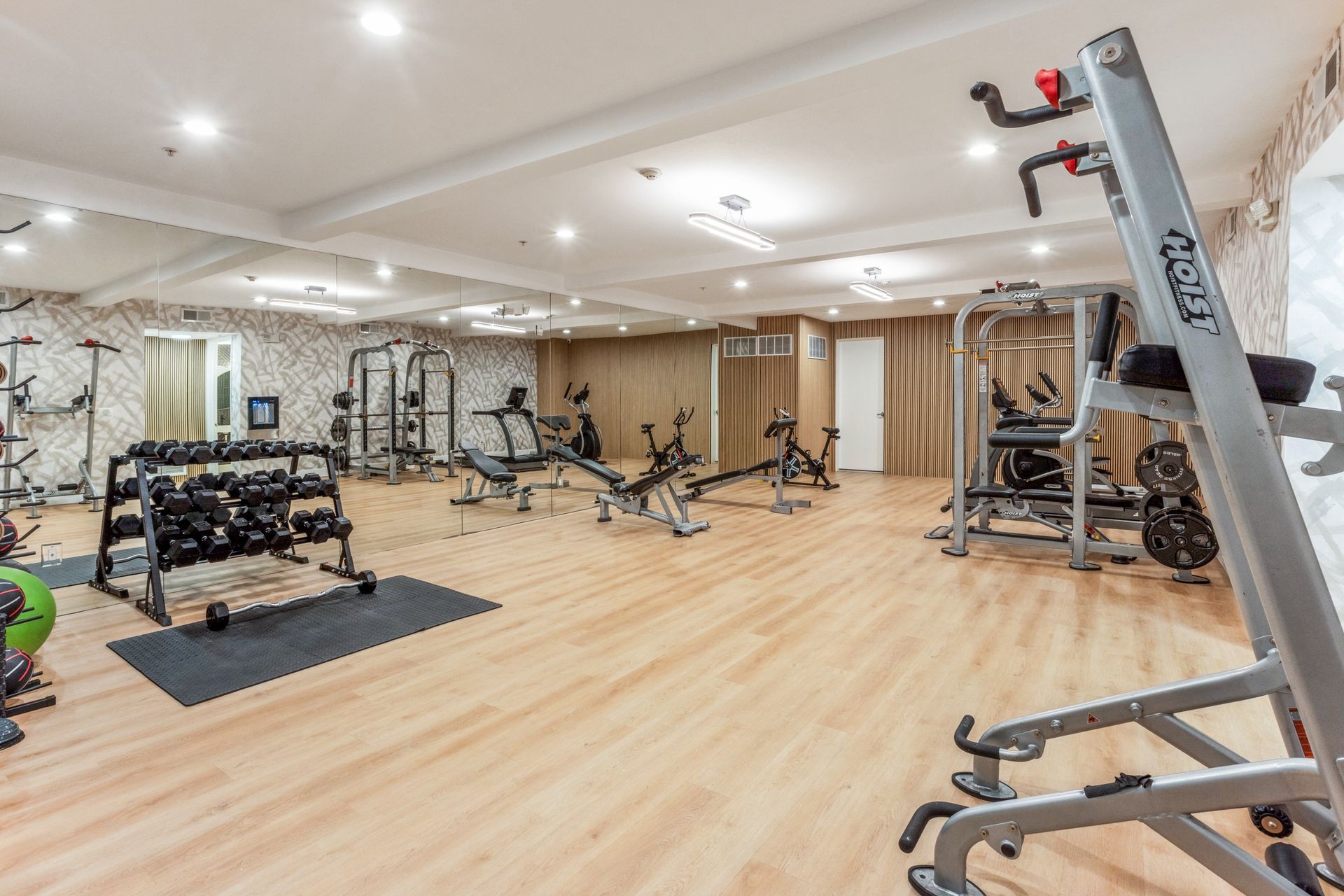 Gym interior with exercise equipment on wood floor.