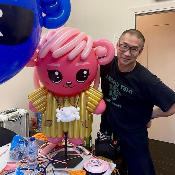 A man in a black shirt that says diet choice stands next to a stuffed animal