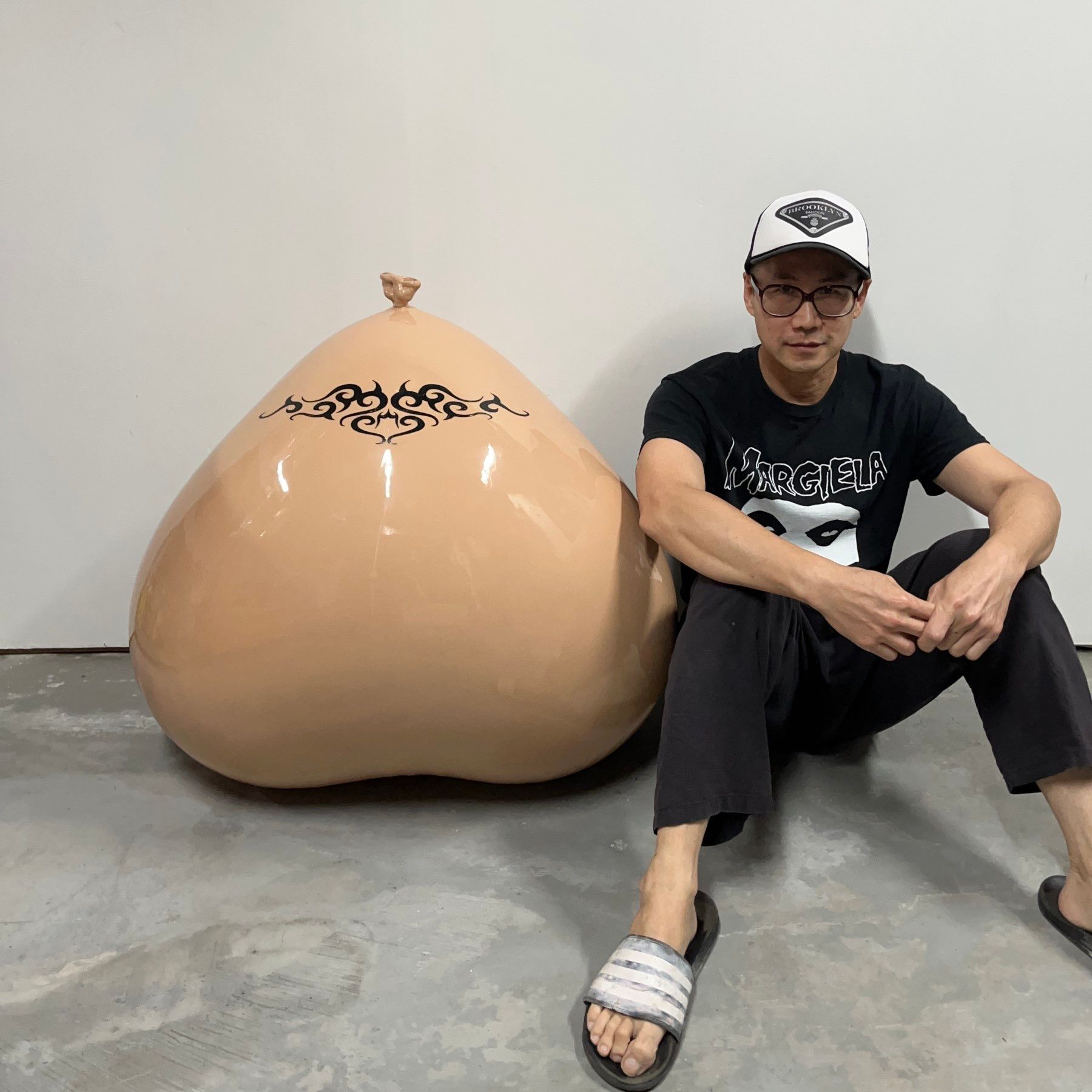 A man is sitting on the floor next to a large sculpture