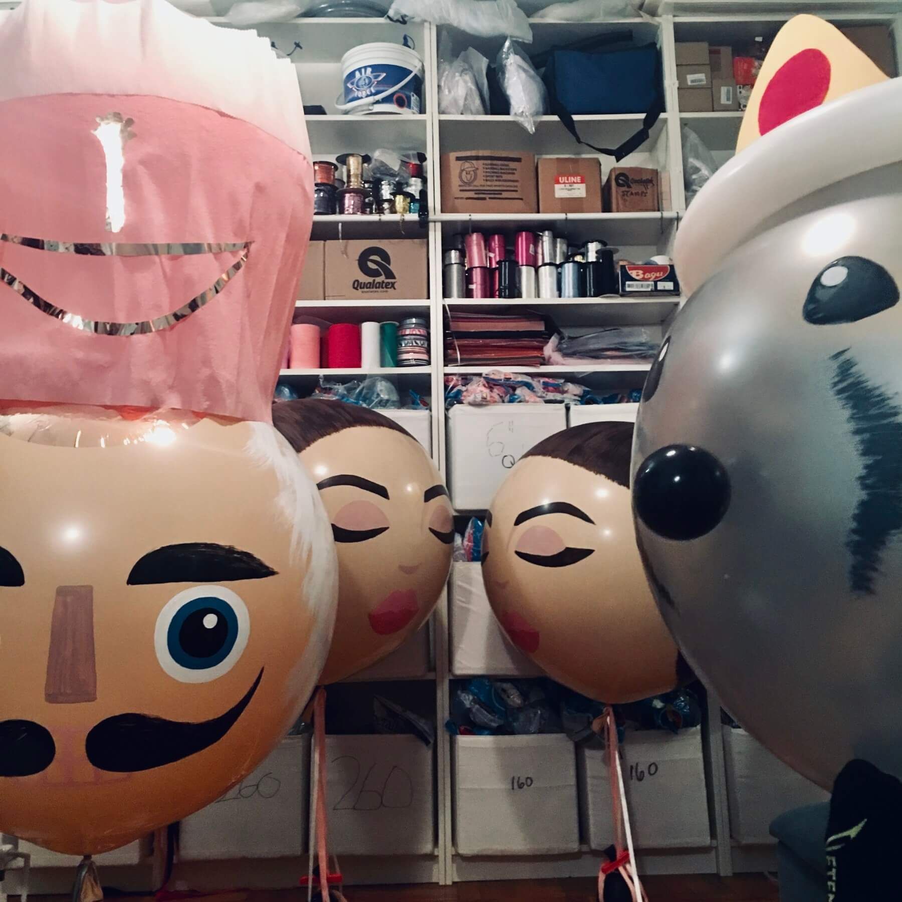 A bunch of balloons with faces on them in a room