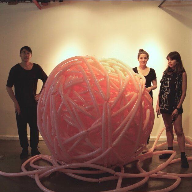 A group of people standing around a large pink ball made of balloons