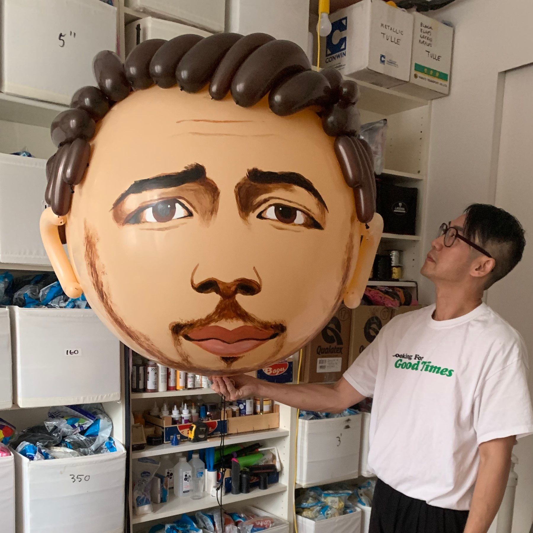 A man in a white shirt is holding a balloon with a face on it