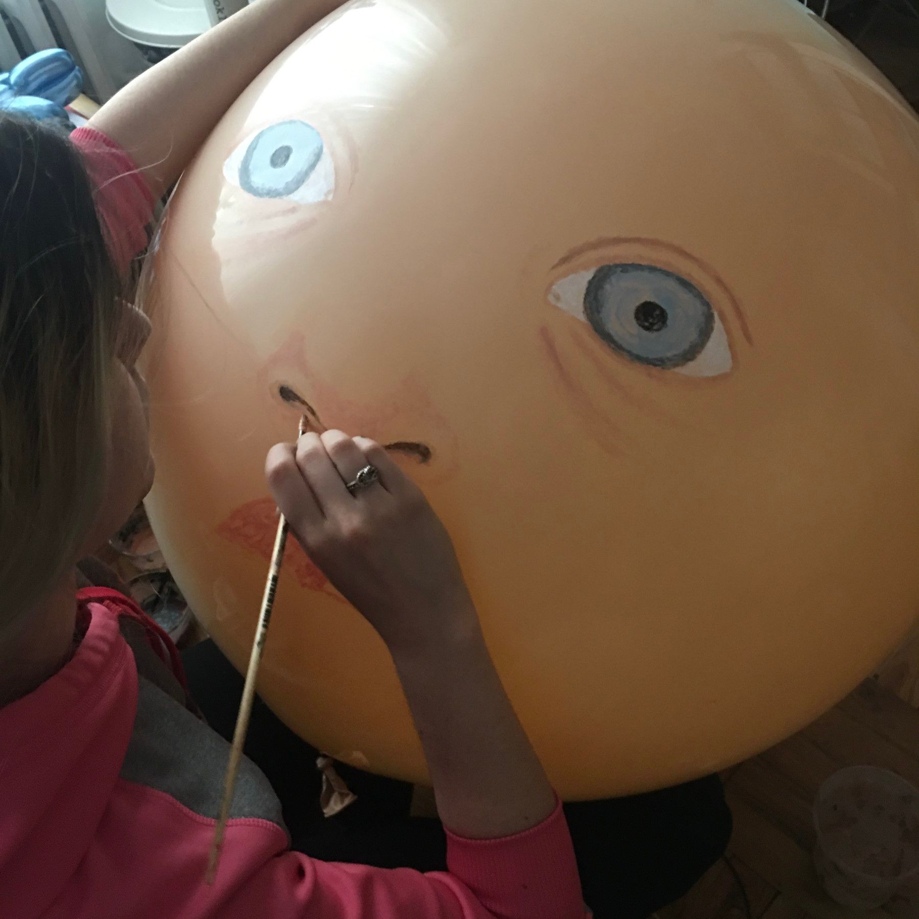 A woman is painting a balloon with a face on it