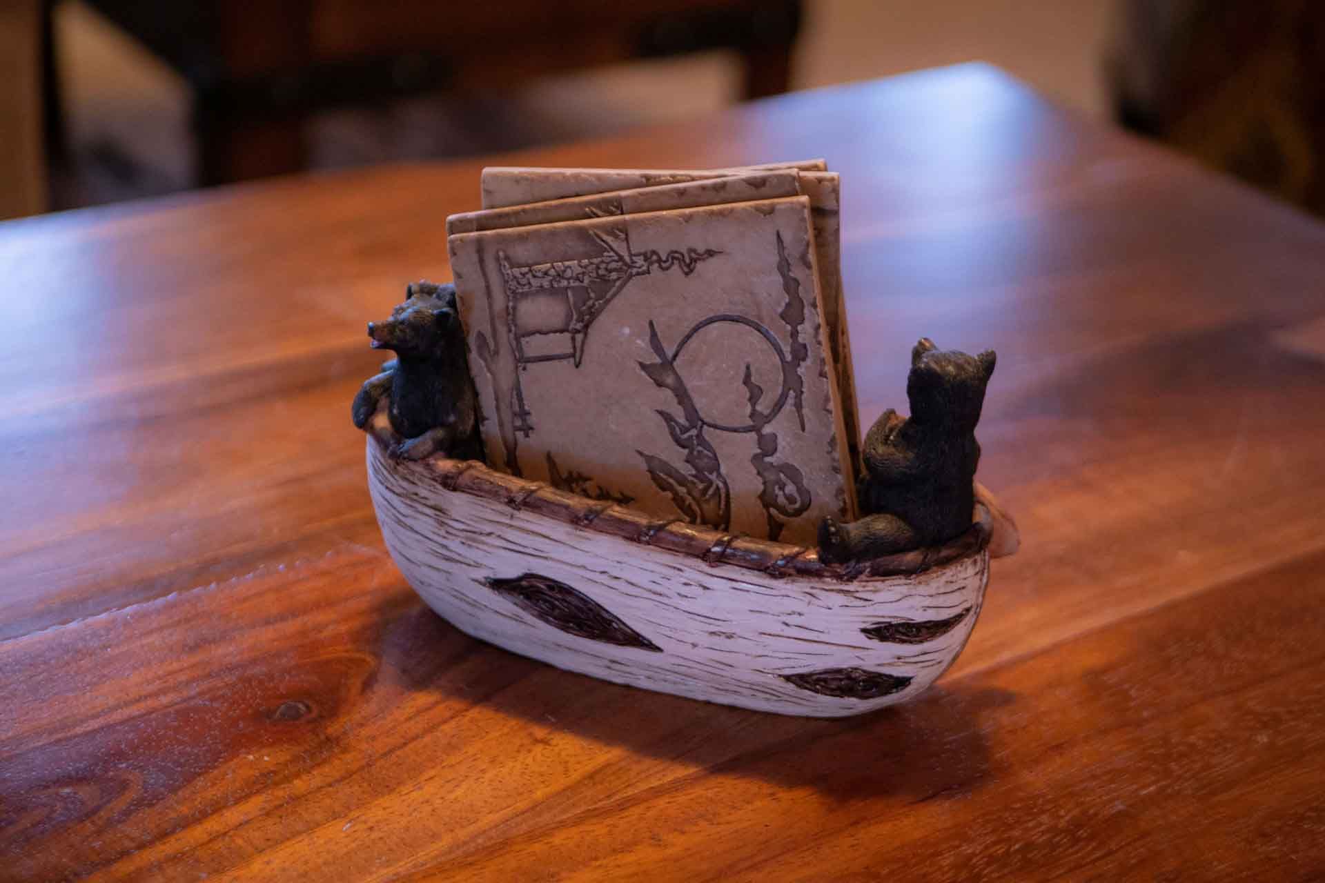 A small boat with two bears in it is sitting on a wooden table.
