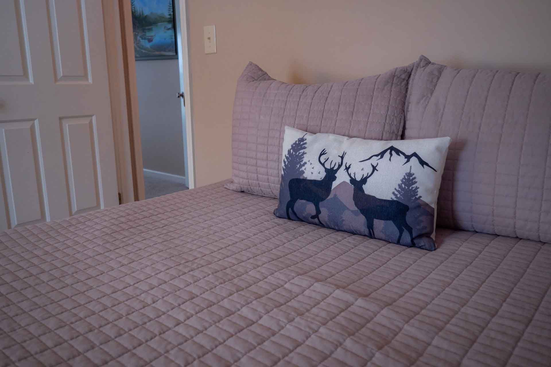 A bed with a deer pillow on it in a bedroom.