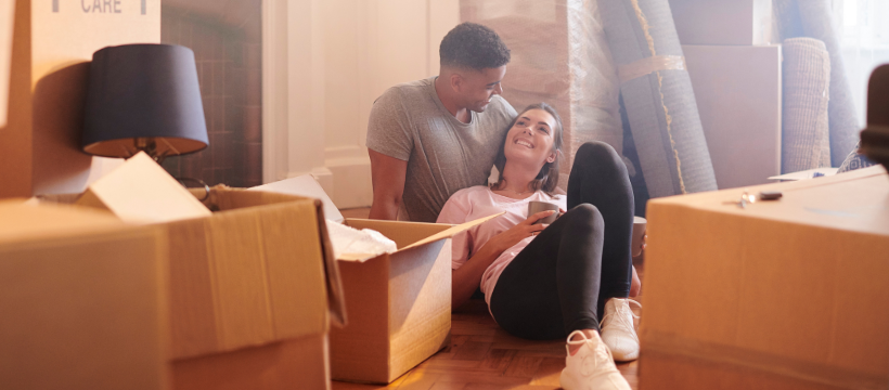 Happy couple relaxing amidst moving boxes in their new home, embodying the joy of homeownership after successfully navigating the real estate market as first-time home buyers in Spokane.