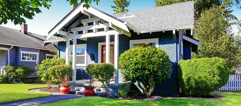 Charming blue single-family home in Spokane, Washington, showcasing well-manicured landscaping and a welcoming front porch, highlighting the type of property appraised in a VA home loan process.