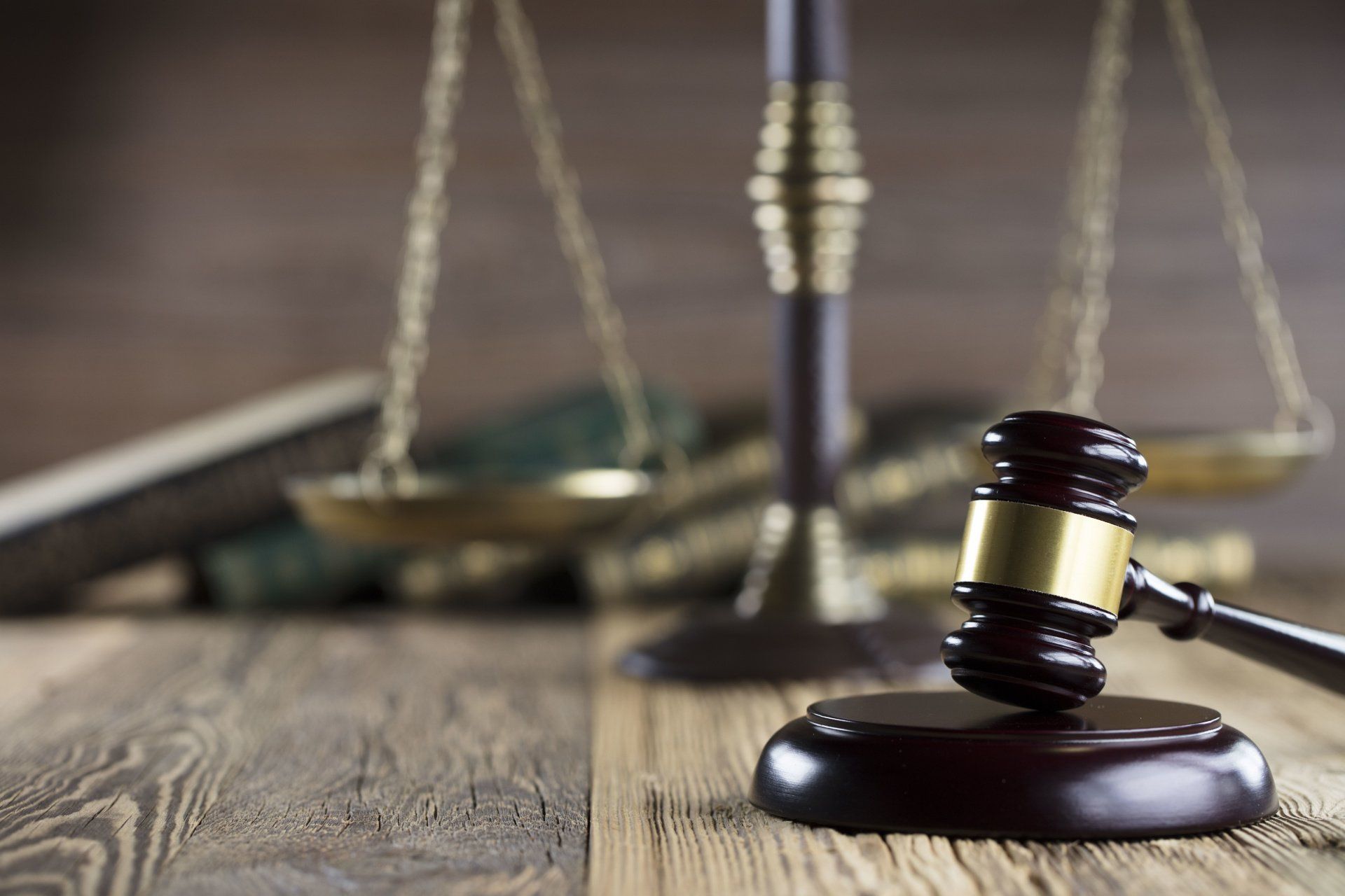 A judge 's gavel is sitting on a wooden table next to a scale of justice.