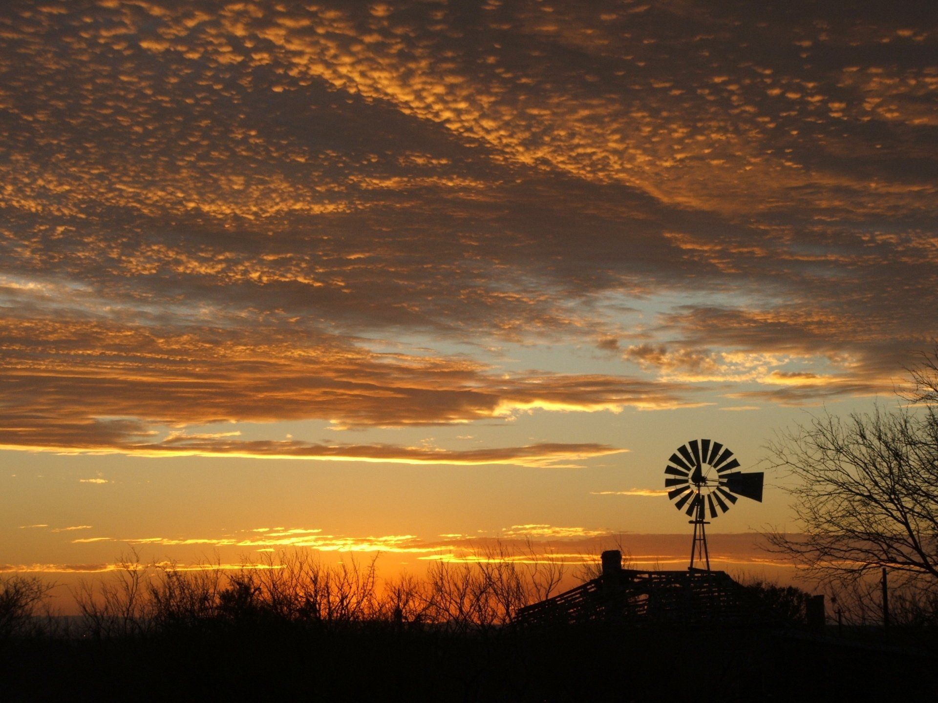 A windmill is silhouetted against a sunset sky