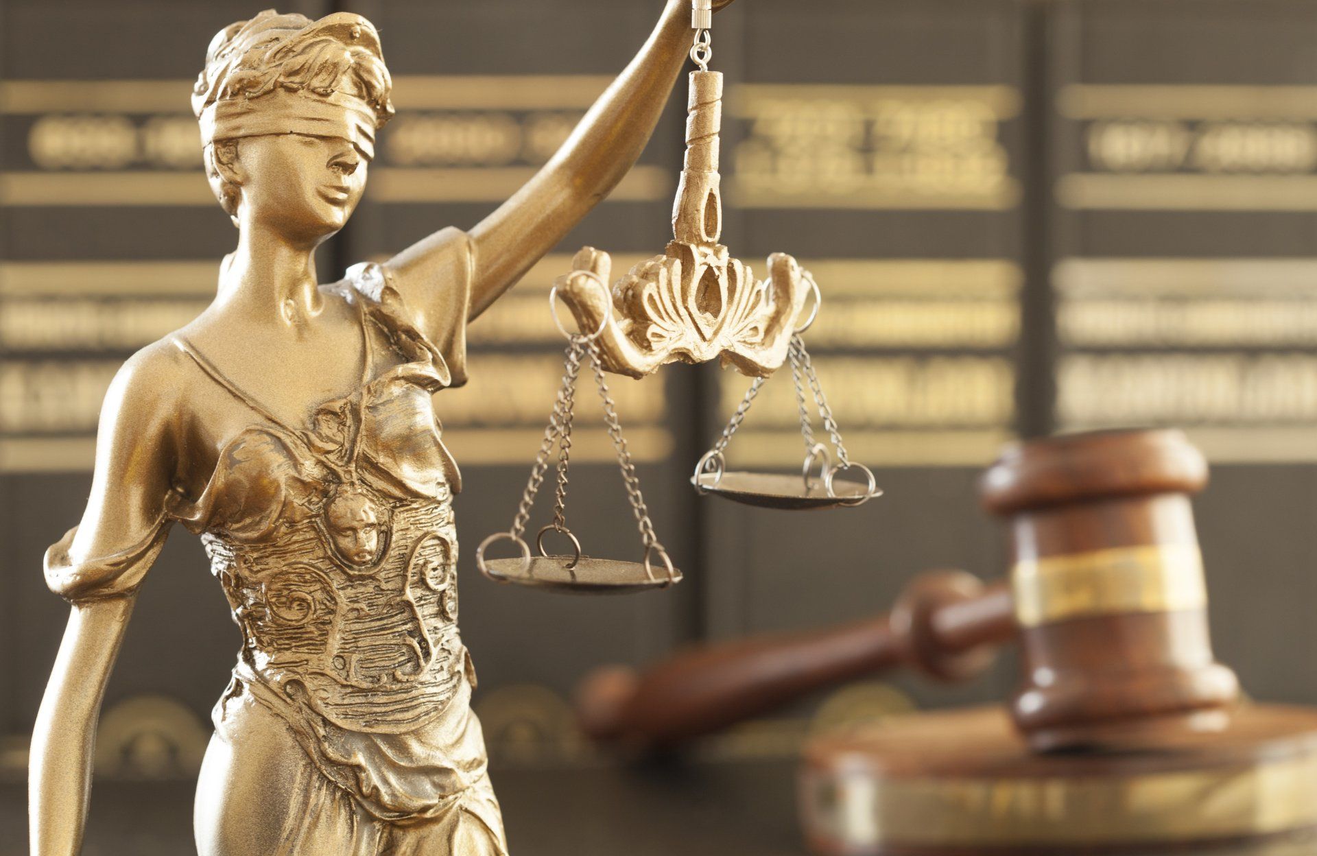 A statue of lady justice holding a scale in front of a judge 's gavel