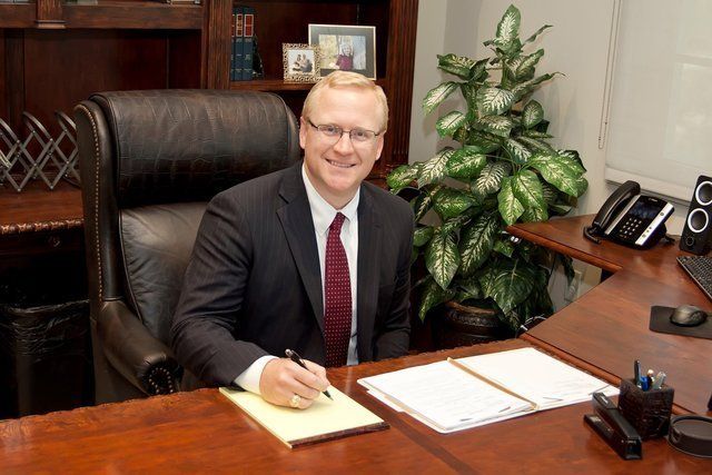 A man in a suit and tie is sitting at a desk.