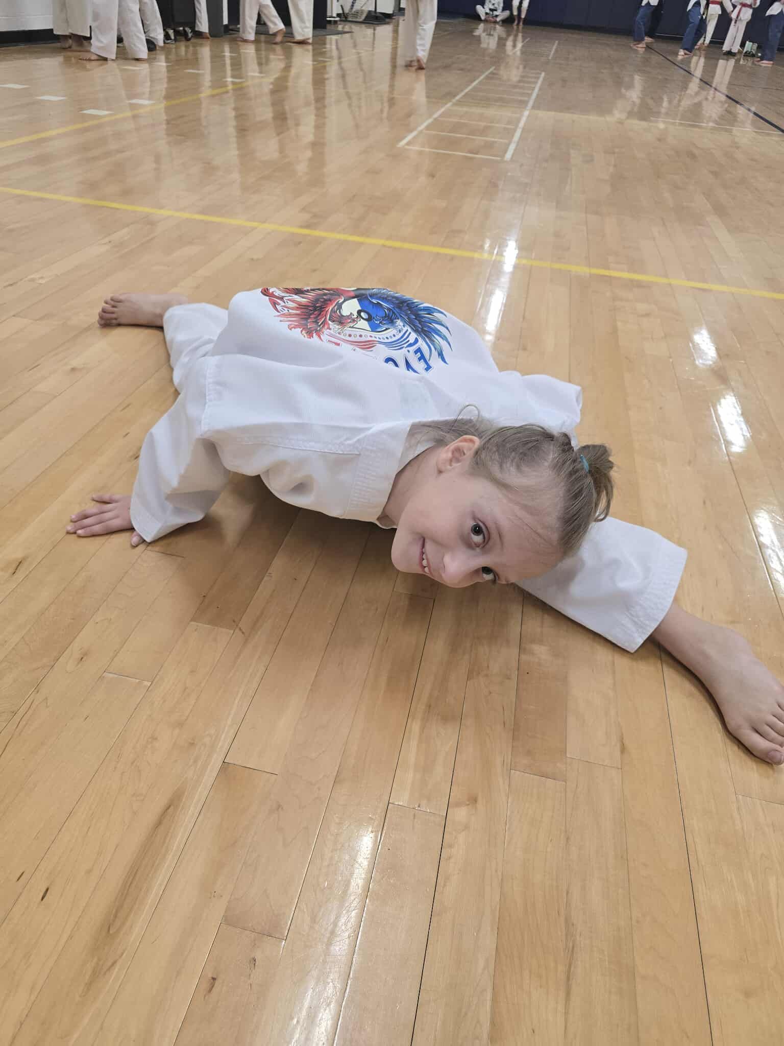 A group of young girls are practicing karate in a gym.
