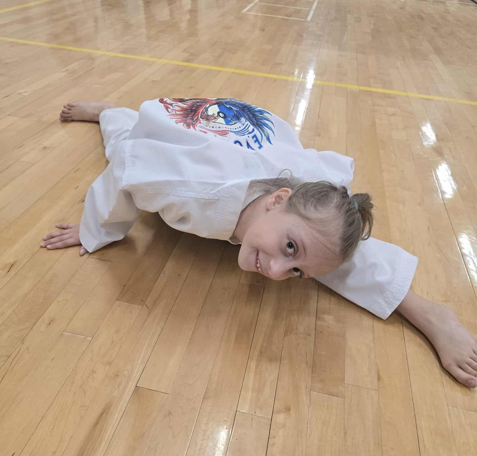 A group of young girls are practicing karate in a gym.
