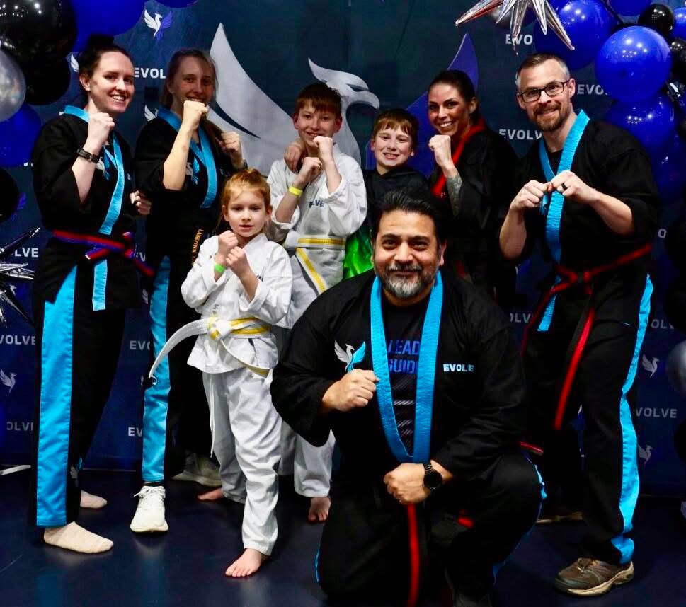 A group of young children in karate uniforms are posing for a picture.
