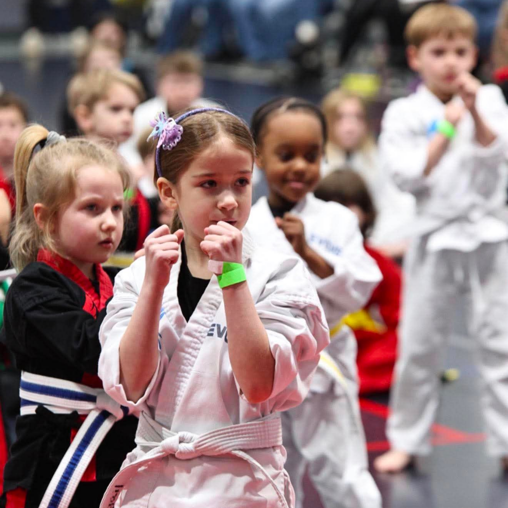 A man is kneeling down next to a young boy in a taekwondo class.
