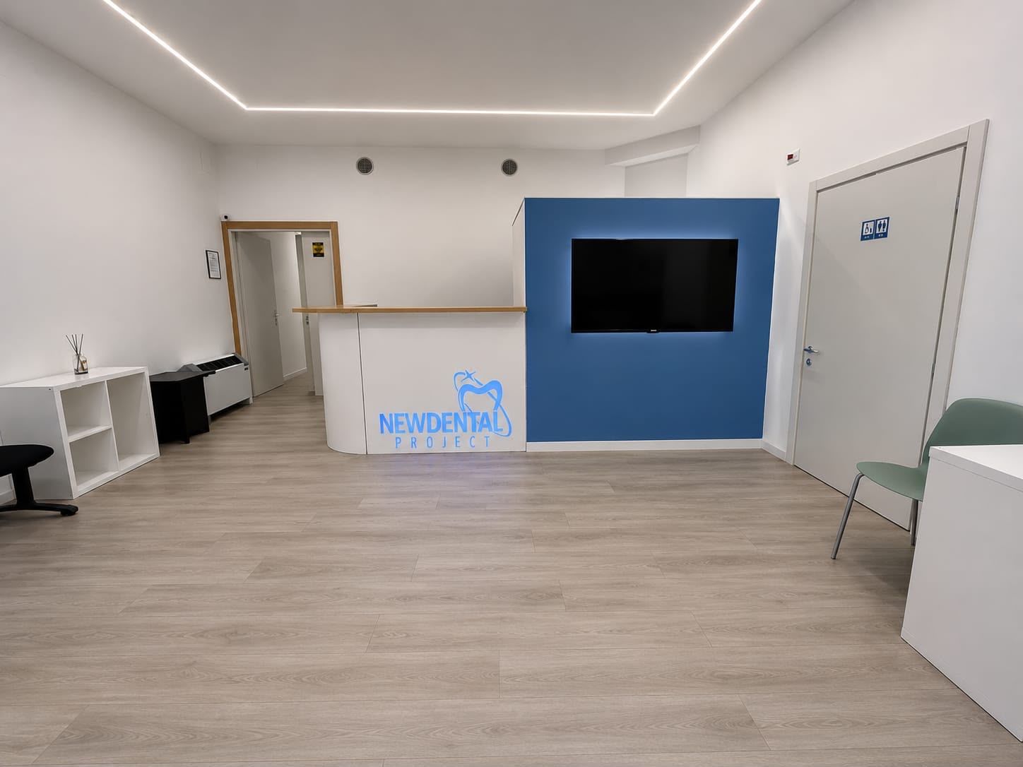 Reception di uno studio dentistico con scrivania nera, pavimento piastrellato e cartello 
