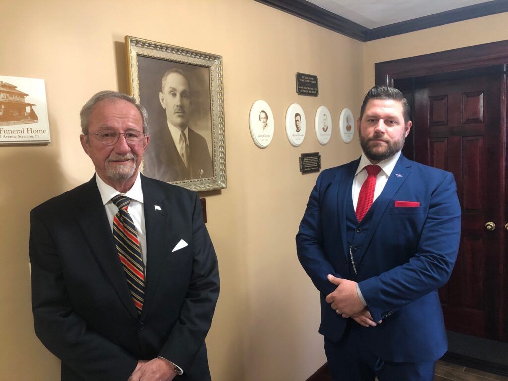 The front door of a house with a porch and plants in front of it.