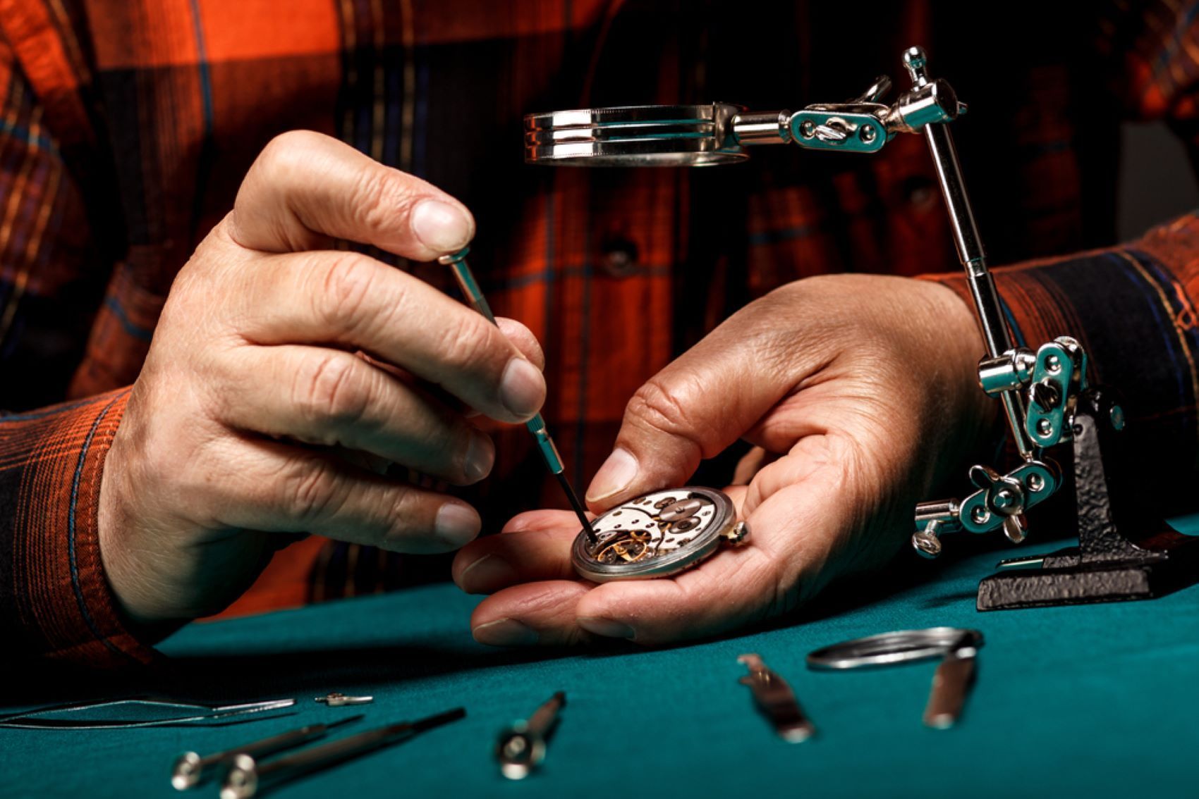 A Man is Fixing a Watch With a Screwdriver — Coastal Clocks & Watches in Mooloolaba, QLD