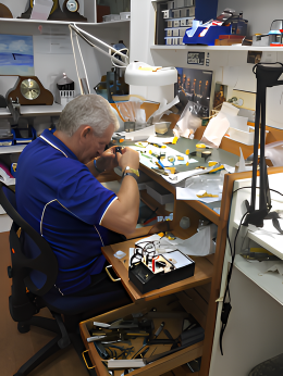 A Man in a Blue Shirt is Working on a Watch — Coastal Clocks & Watches in Buddina, QLD