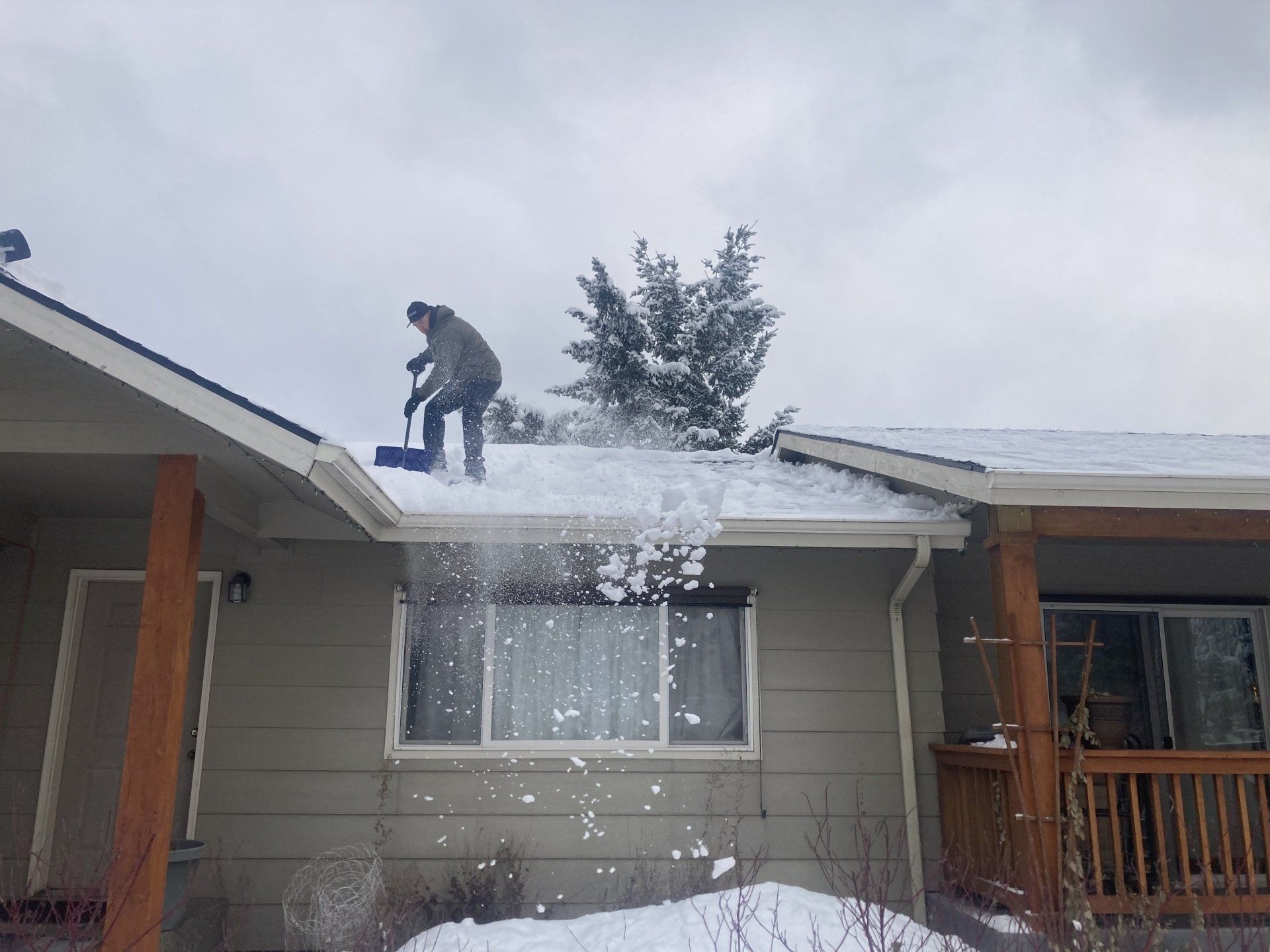 shoveling snow from the roof of a customer .