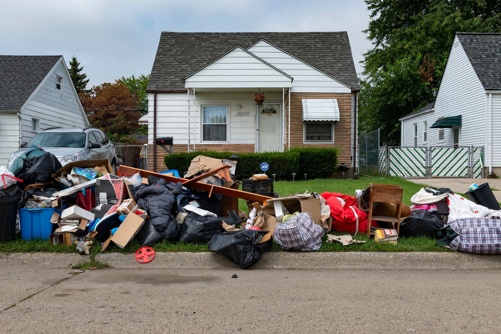 A pile of trash is sitting on the side of the road in front of a house.