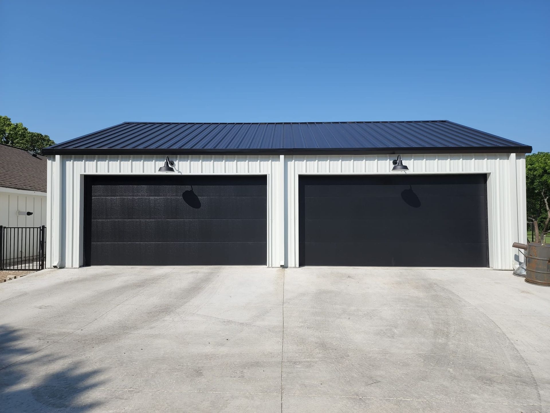 A white garage with black garage doors and a blue roof