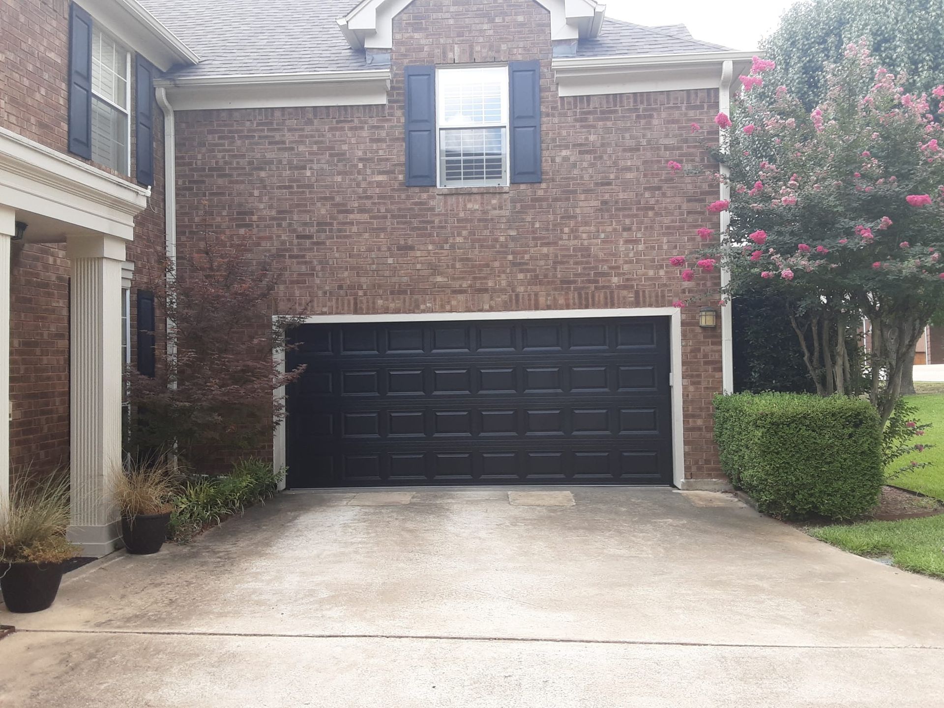 A brick house with a black garage door and a driveway.