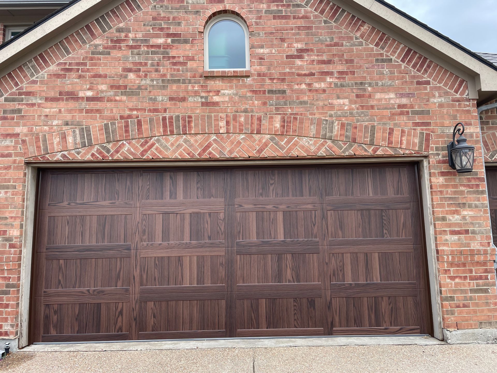 A brick house with a wooden garage door and a window.