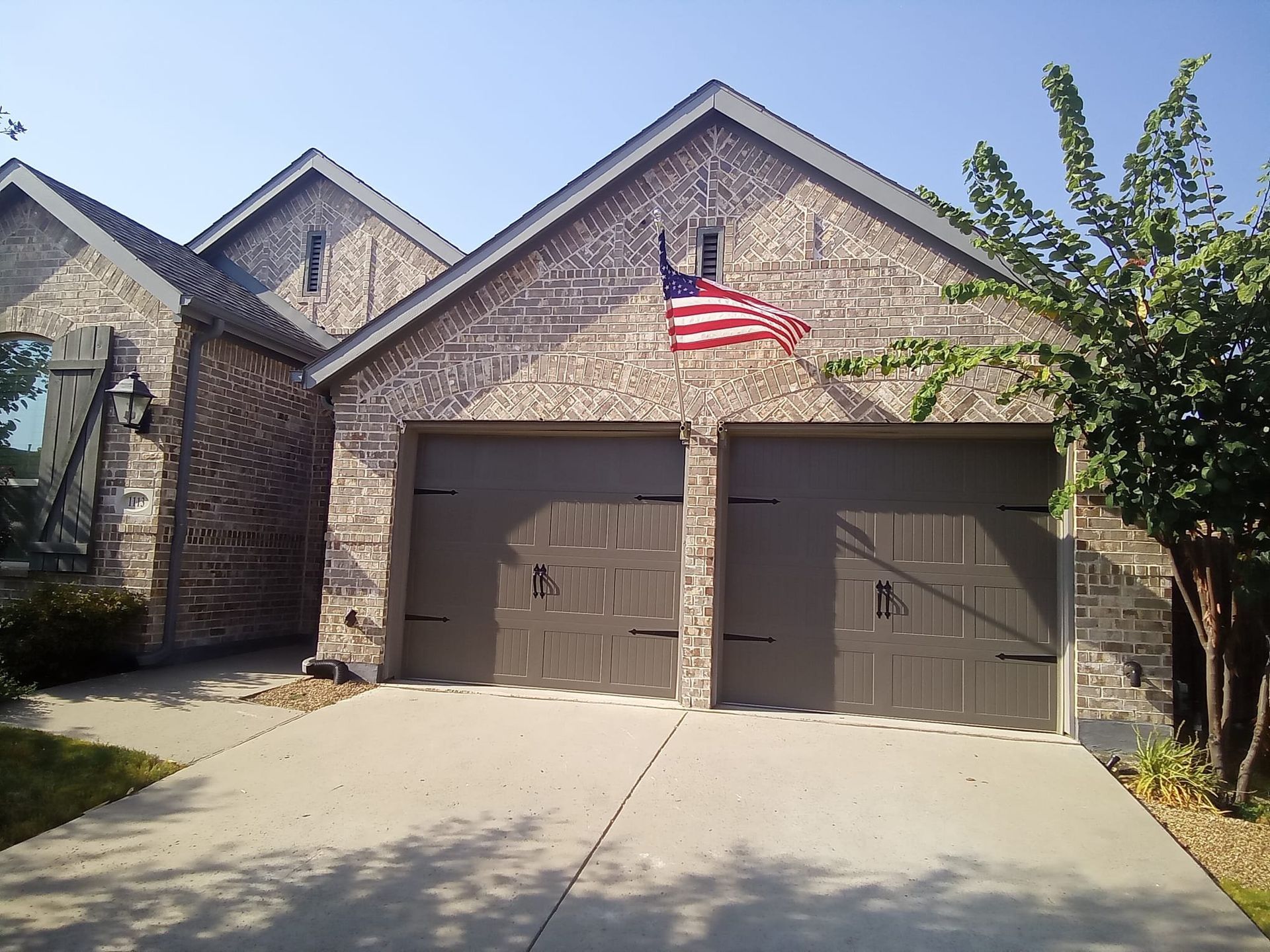 A brick house with two garage doors and an american flag