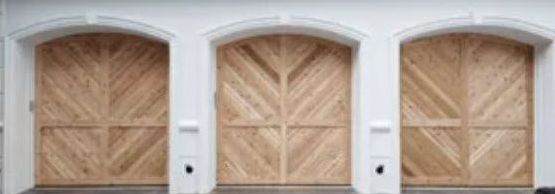 Three Wooden Garage Doors Are Sitting Next to Each Other on A White Building.