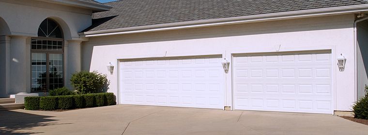A white house with two white garage doors and a gray roof