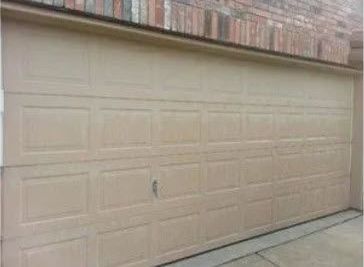 A Tan Garage Door Is Sitting in Front of A Brick Building.