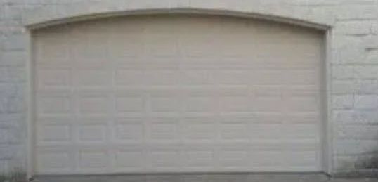 A White Garage Door with A Curved Arch on A Brick Building.