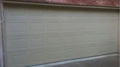 A White Straight Garage Door Is Sitting on The Side of A Brick Building.