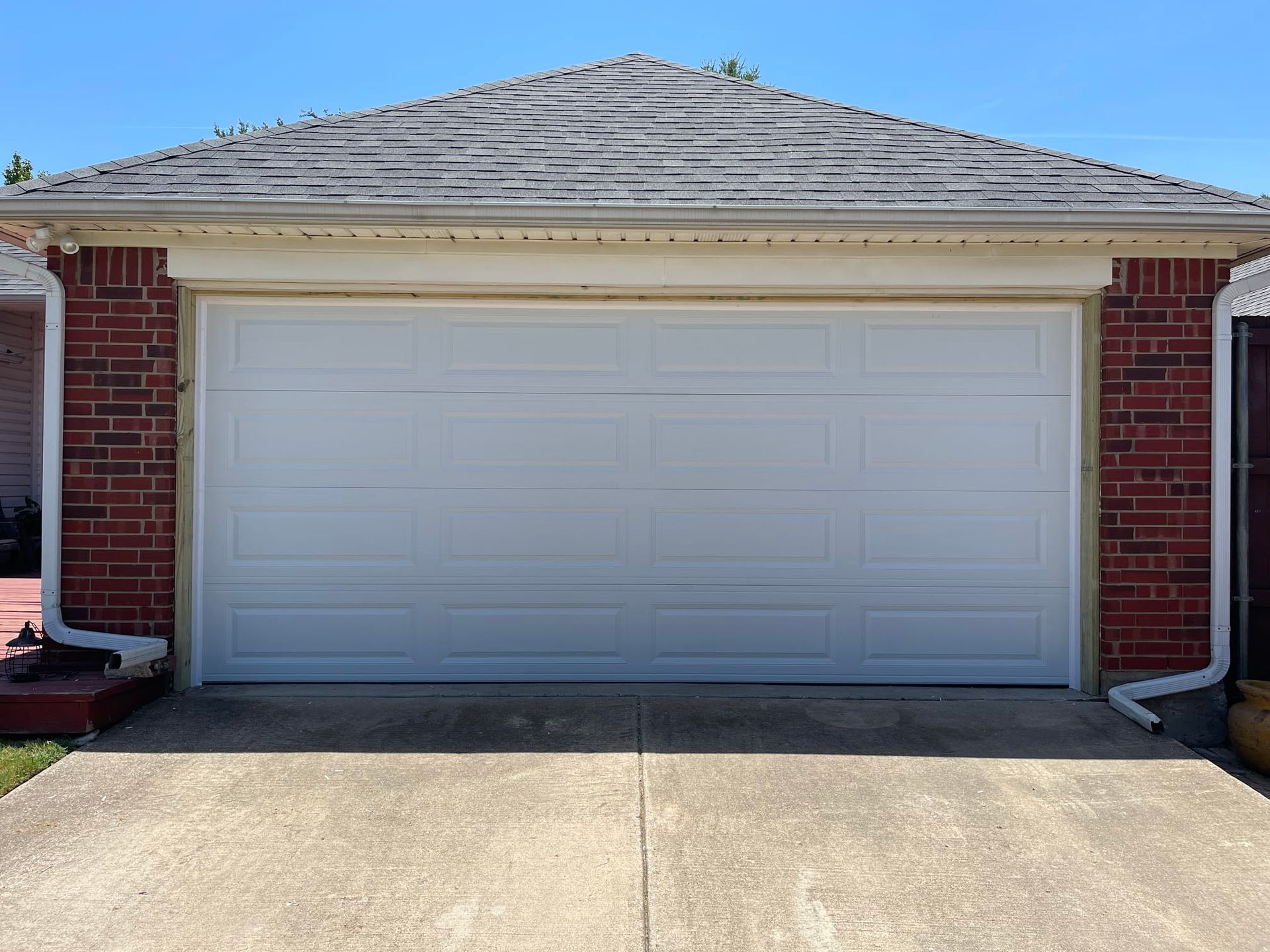 A white garage door is sitting in front of a brick house.