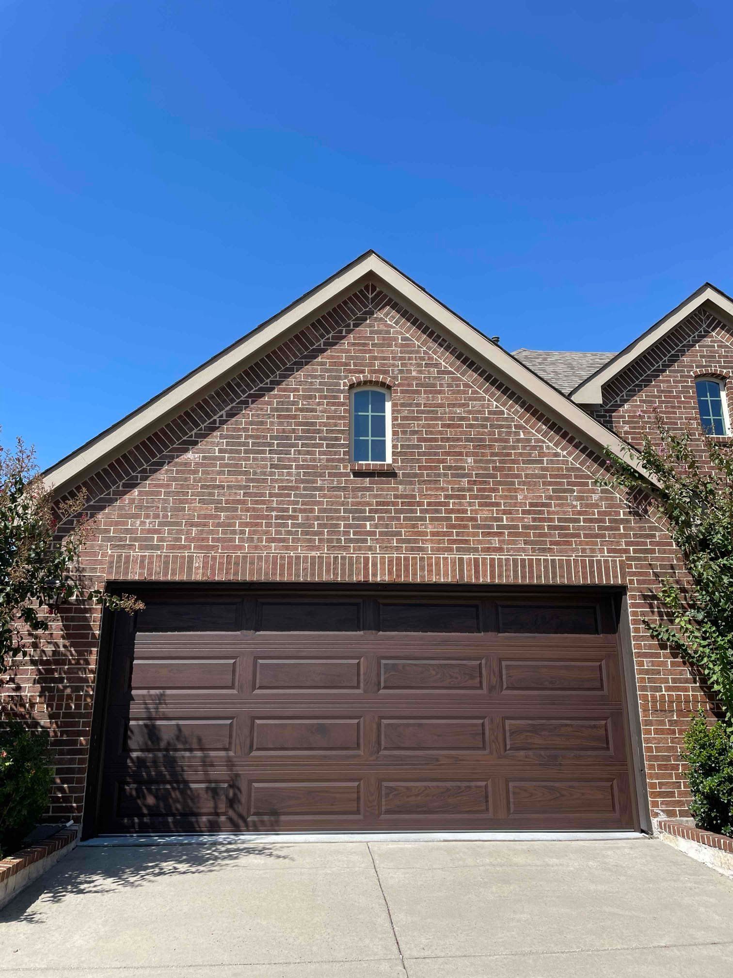 A brick house with a brown garage door and a window.