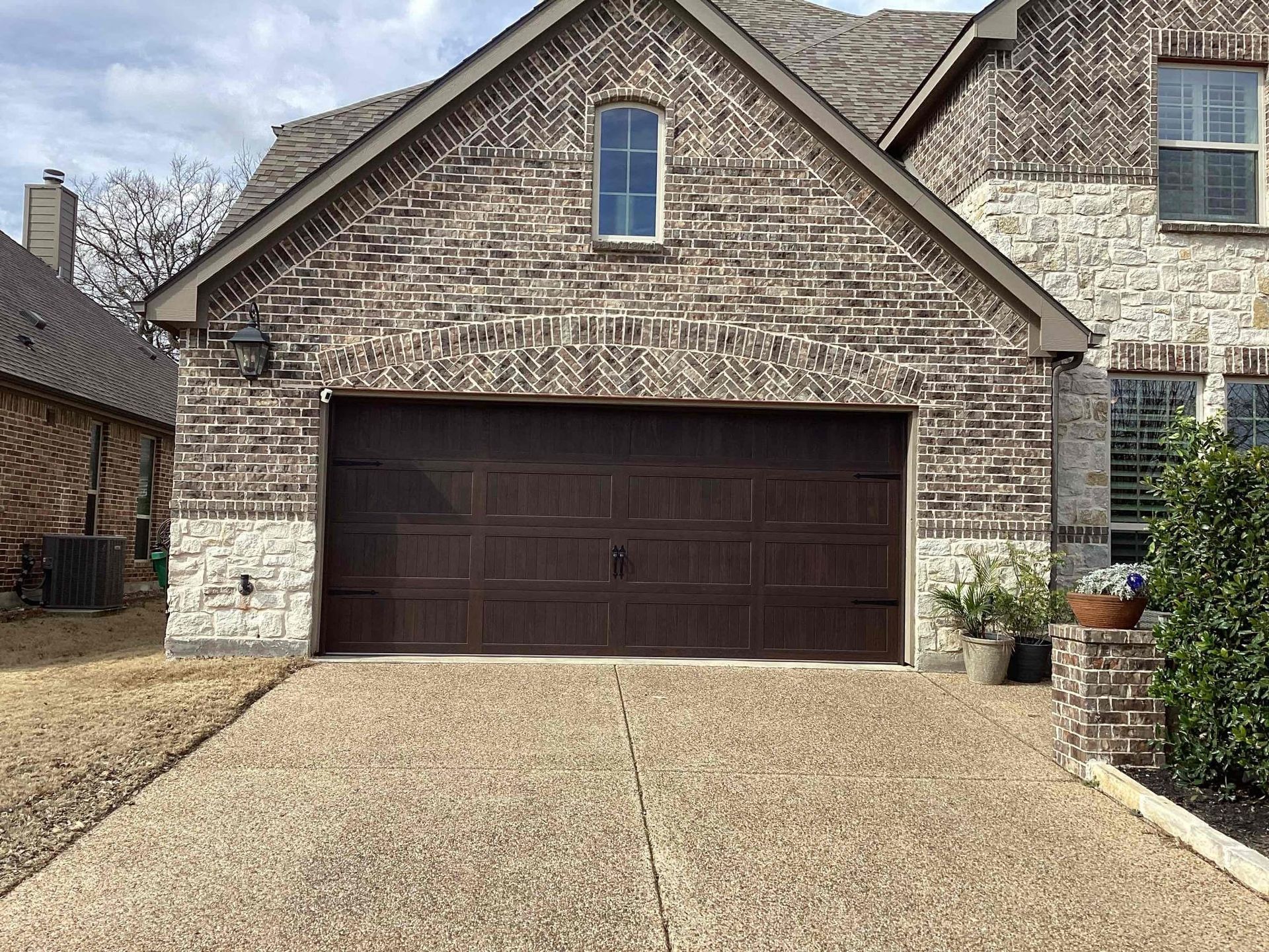 A large brick house with a brown garage door.