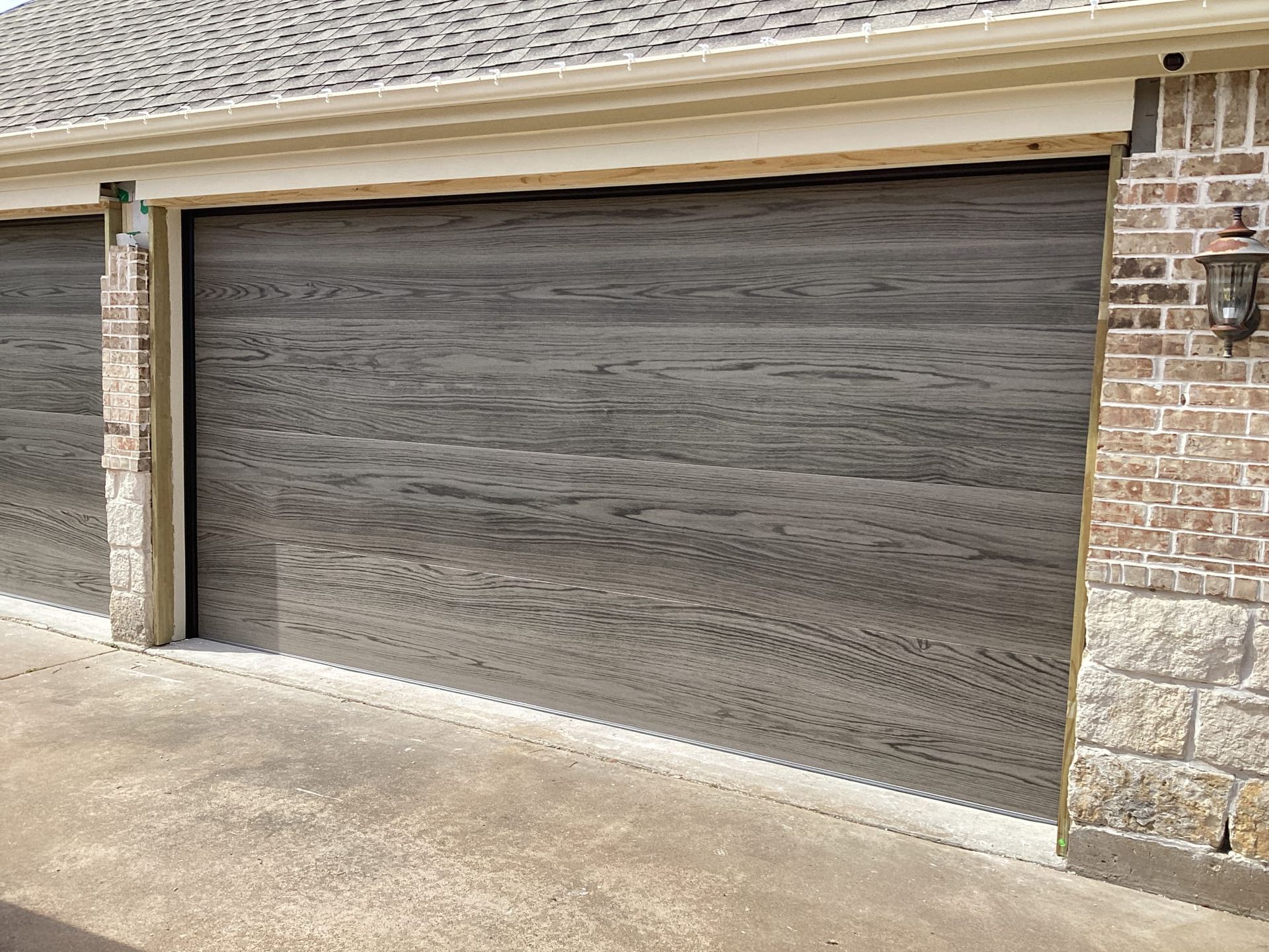 A garage door that looks like wood is on a brick building.