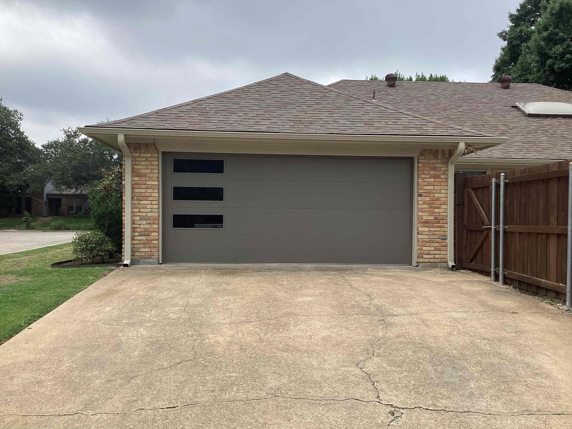 A house with a gray garage door and a wooden fence.