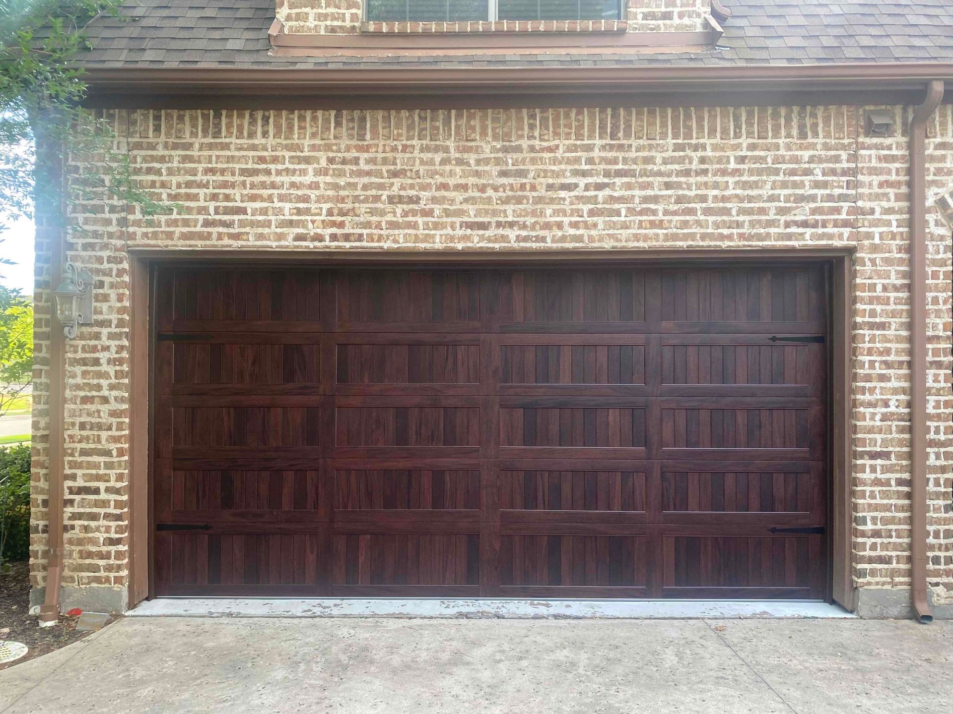 A brown garage door is on a brick building.