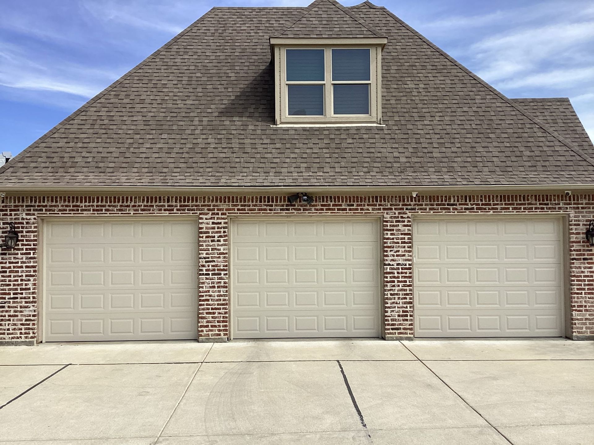A house with three garage doors and a window on the roof
