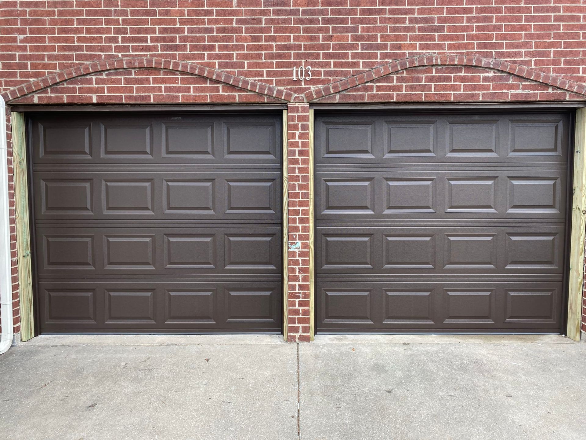 A pair of brown garage doors on a brick building