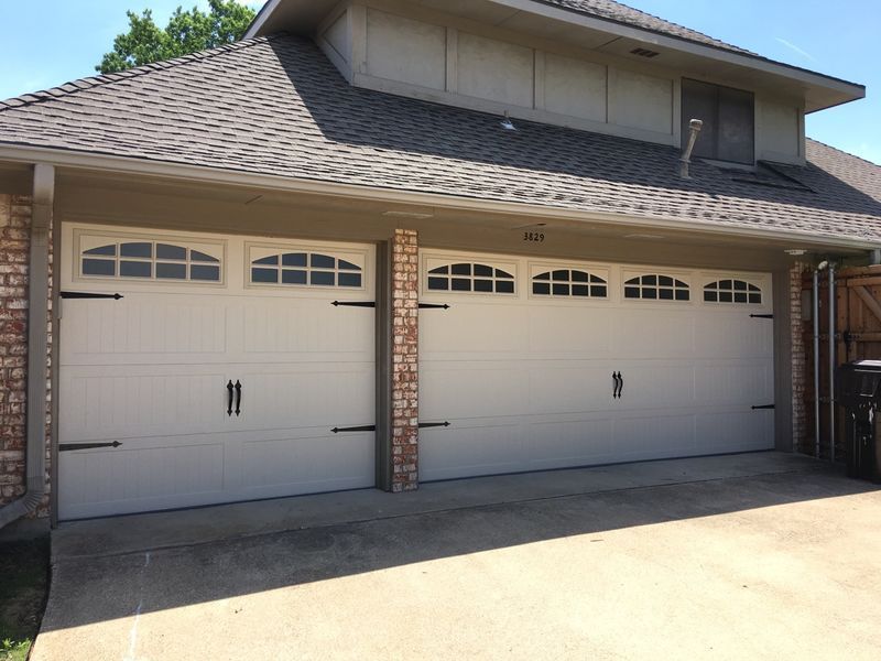 A white garage door is sitting in front of a brick house.