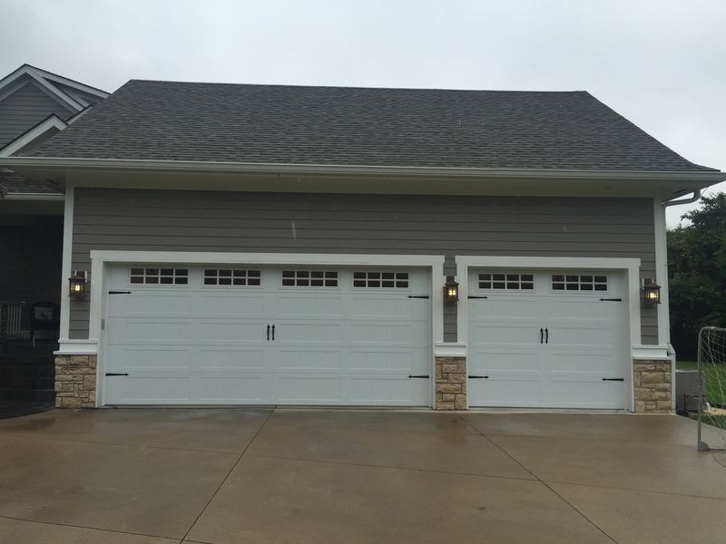 There are two garage doors on the side of a house.