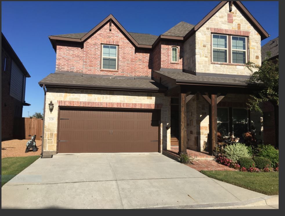 A large brick house with a brown garage door