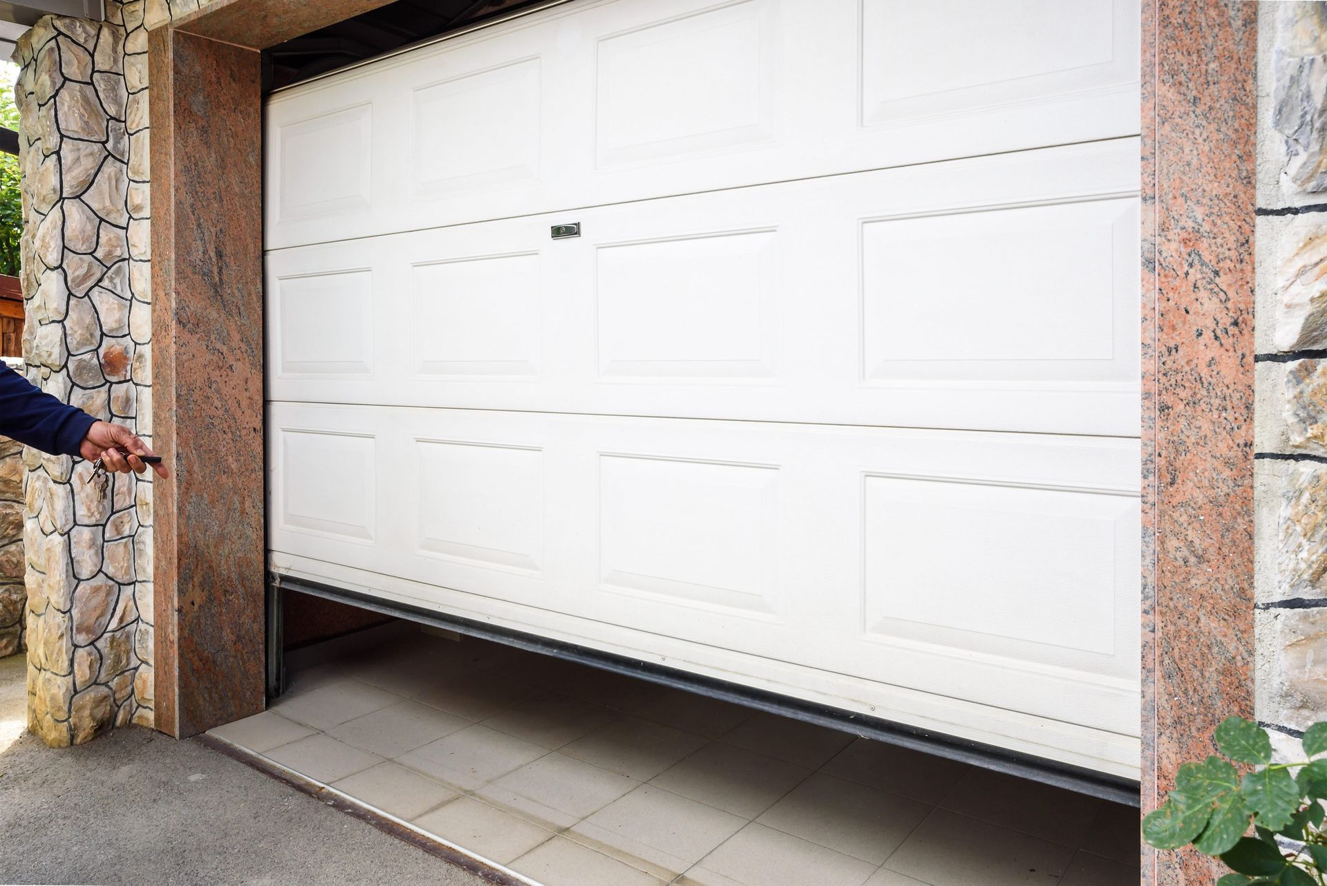 White PVC electric garage door installed on a stone wall. White PVC electric garage door installed on a stone wall.
