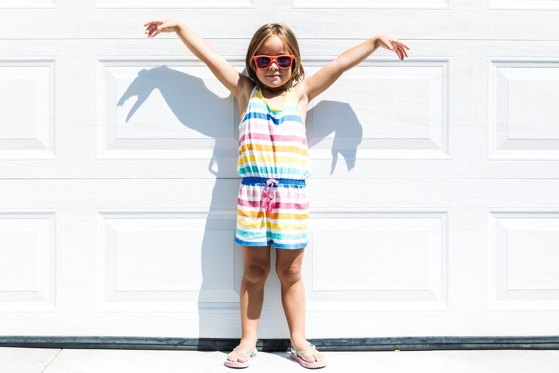 Little girl playing against a white garage door.