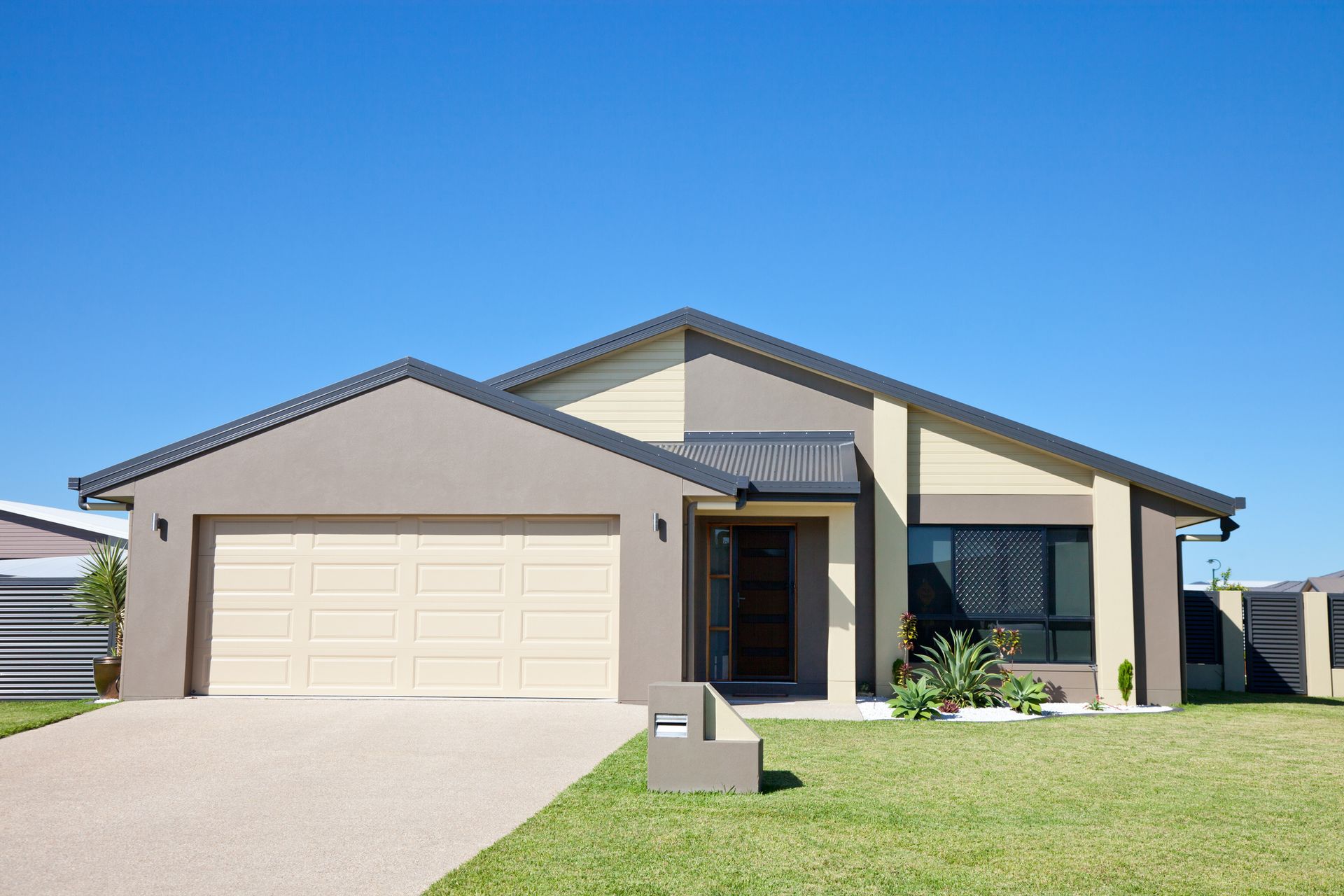 View of a modern single-level home with green grass, after a custom garage door replacement.