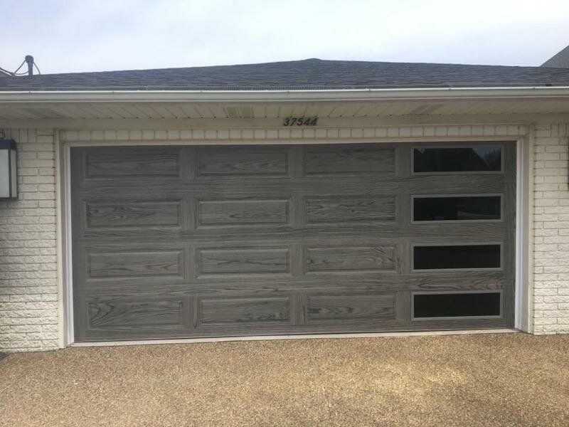A white brick house with a gray garage door.
