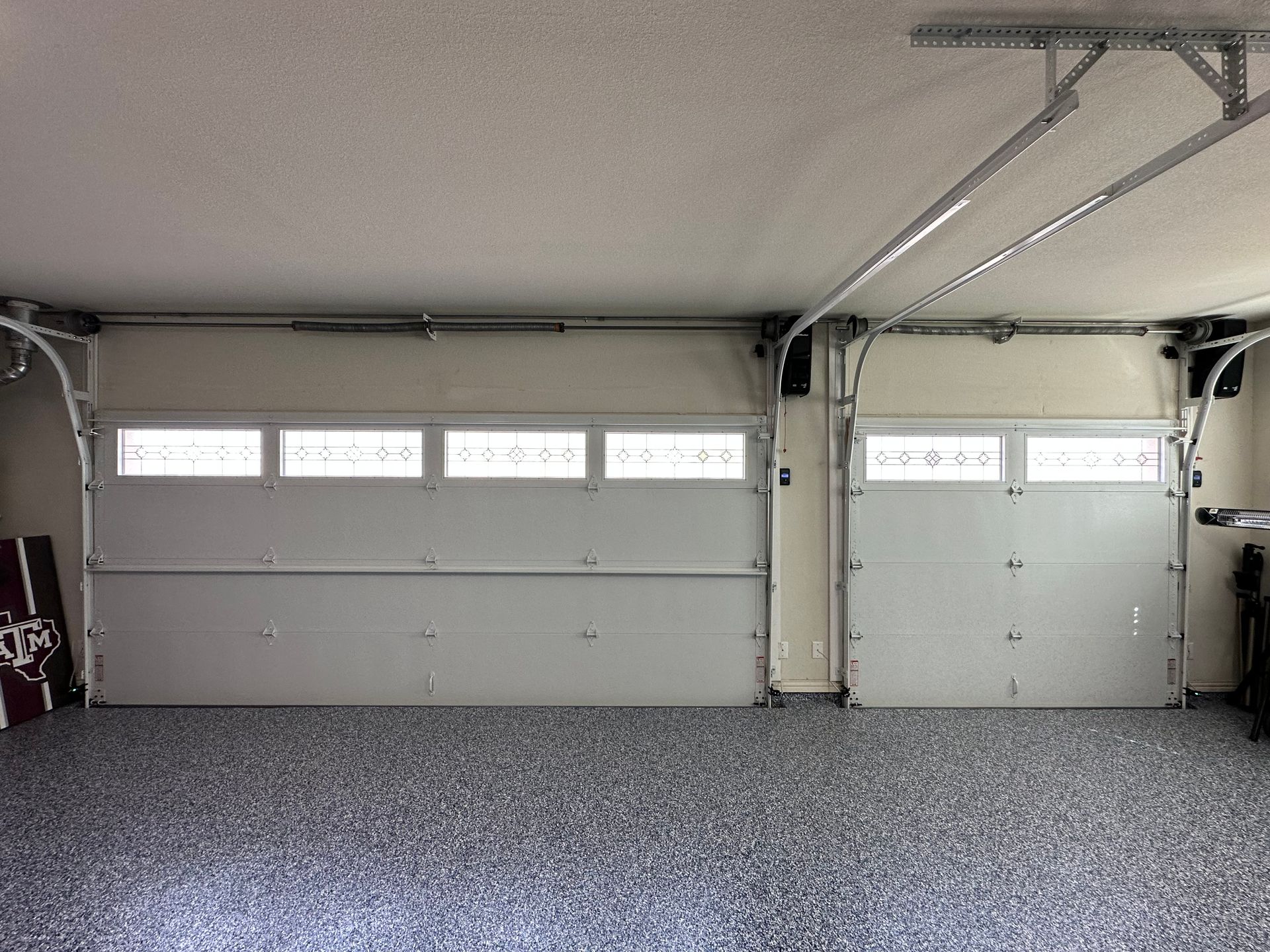 A garage with two garage doors open and a concrete floor.